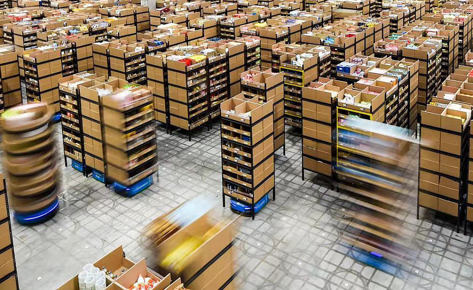 A high-angle view of a robotic warehouse with automated shelving pods moving on a QR-coded floor, illustrating the advanced logistics managed by a Guangzhou warehouse shipping agent.