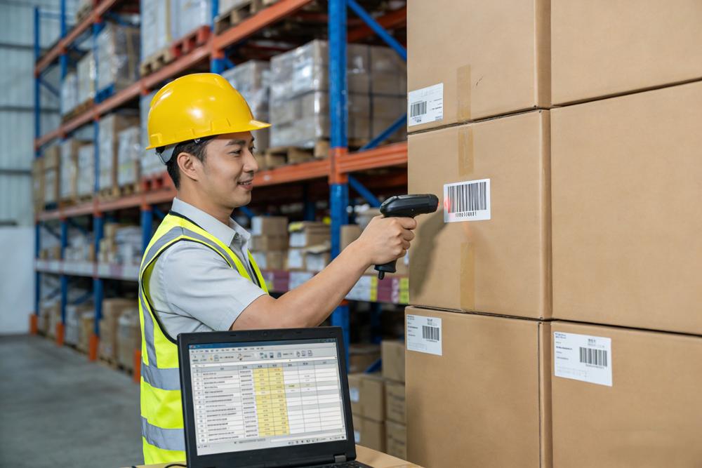 Warehouse employee scanning incoming packages with barcode system for inventory management
