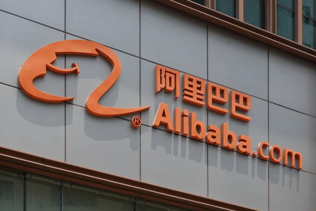 The orange Alibaba.com logo mounted on a grey building facade, representing the platform's corporate infrastructure behind global shipping.

